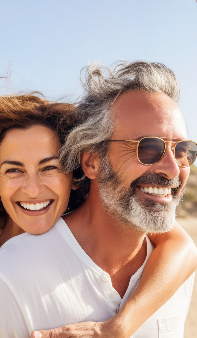Happy middle-aged couple at a beach, woman hugging man from behind