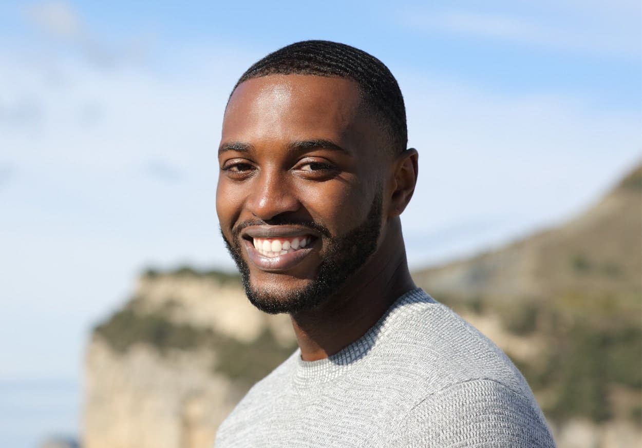 Happy man with black skin looking at camera in nature