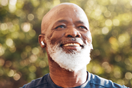 Happy black man running in park with music, smile and mockup in nature, garden and workout. Senior male, outdoor runner and motivation for fitness, energy and healthy exercise training with earphones