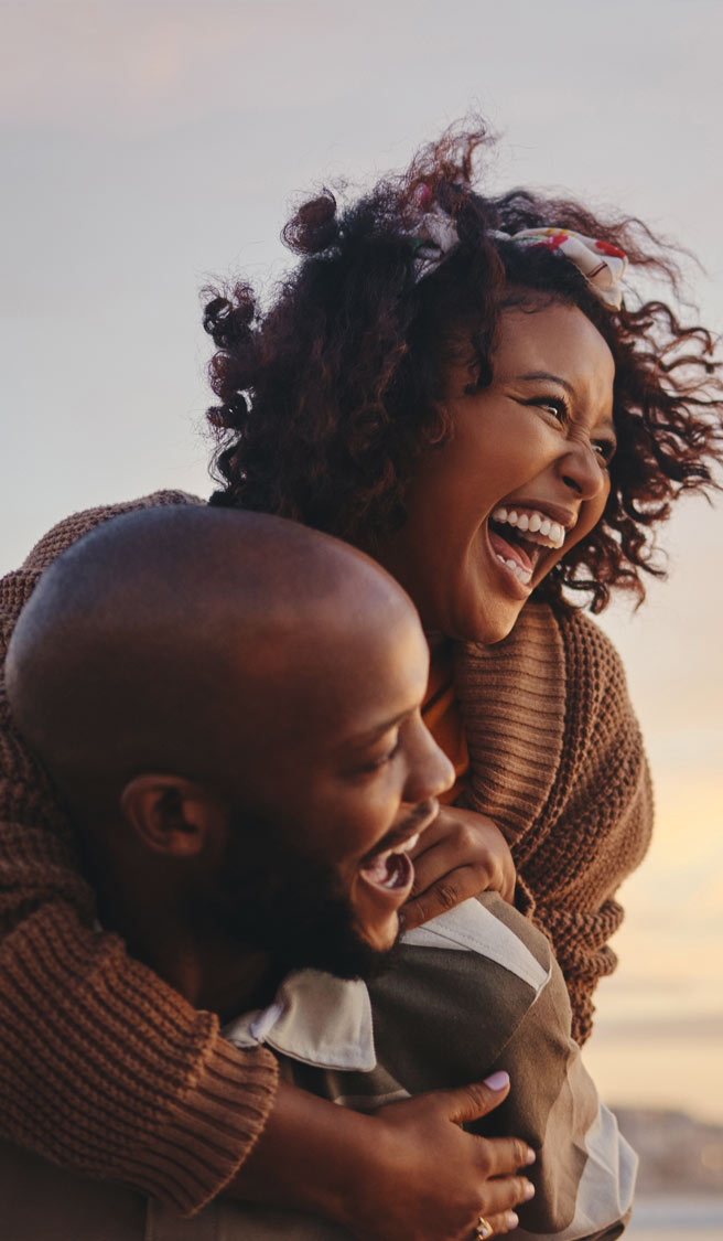 Black couple, travel and beach fun while laughing on sunset nature adventure and summer vacation or honeymoon with a piggy back ride.